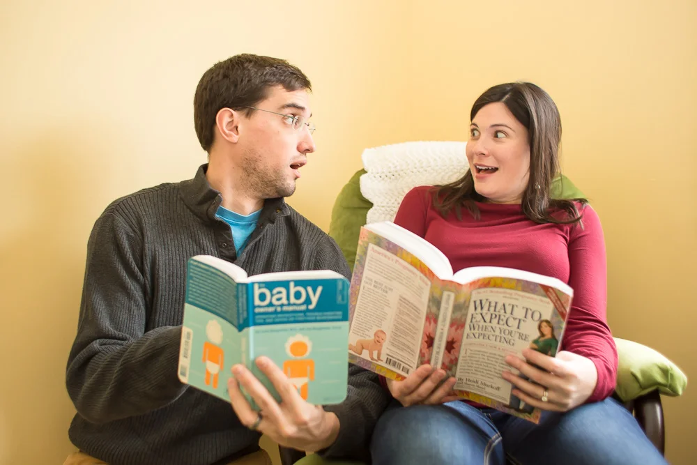 Expectant parents reading “What to Expect When You’re Expecting | In-home Maternity Session