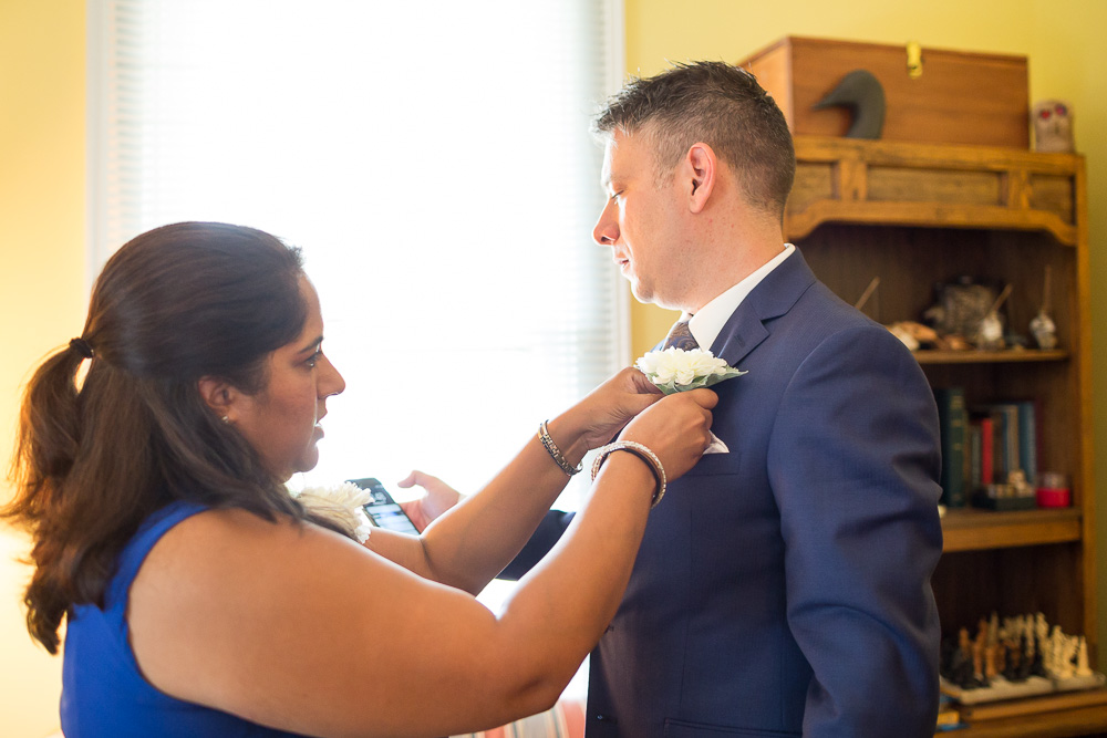 Groom putting on his boutonniere | Candid wedding photography