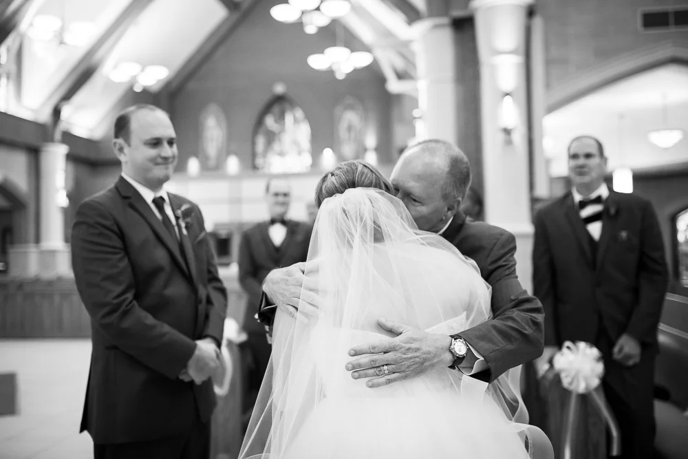 Father of the bride giving her a hug at the altar of St. Theresa Church | Ashburn Virginia Wedding Photographer