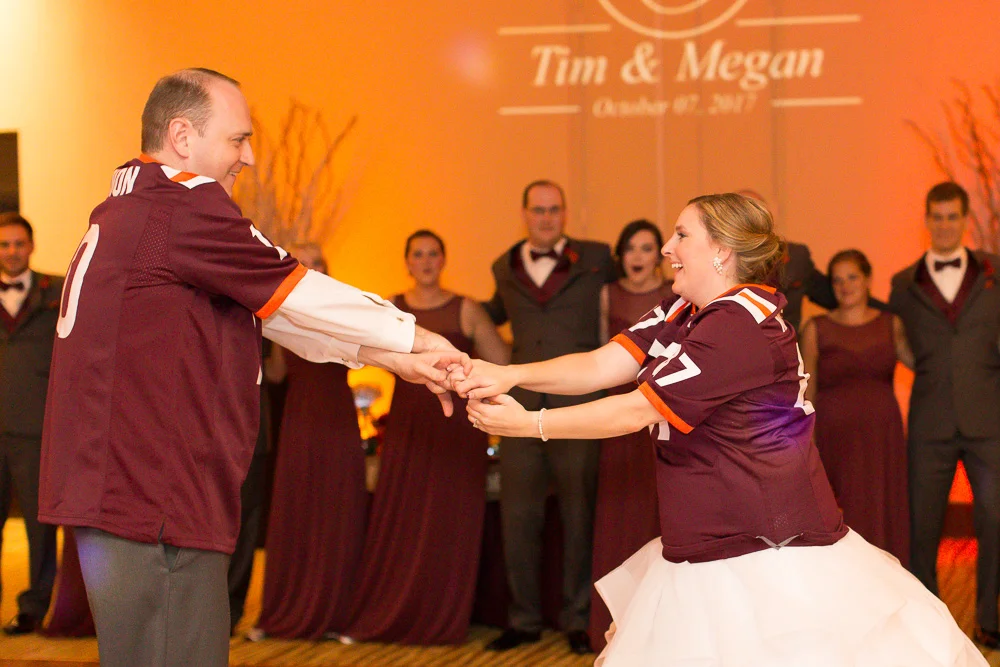 Bride and groom's first dance in their matching Virginia Tech jerseys | Maroon and orange uplighting by Dominion Wedding Entertainment