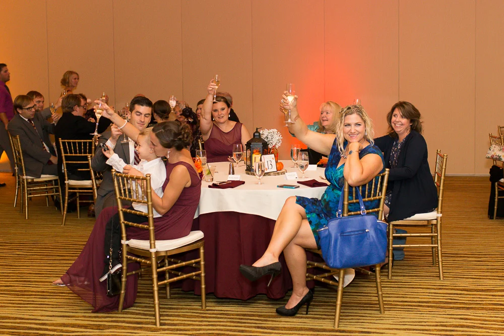 Candid picture of the wedding guests raising their glasses for a toast