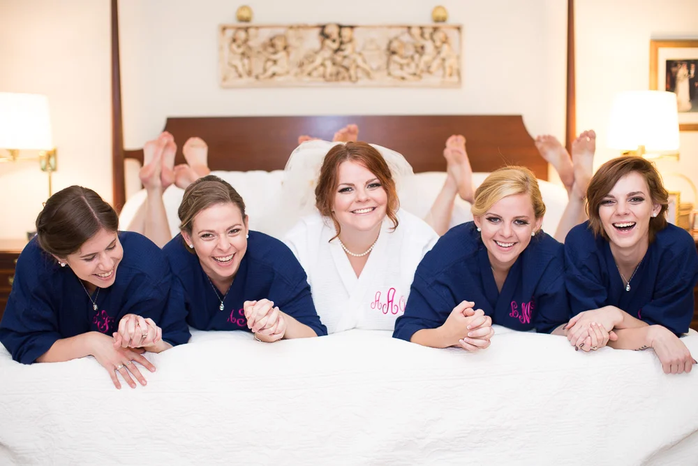 Fun photo of bridal party on the bed in matching bathrobes | Richmond Virginia Wedding