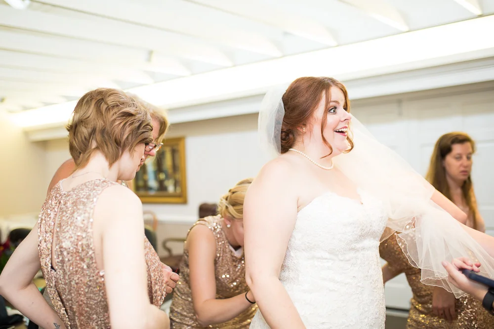 Zippering up the wedding dress at Fox Hall Clubhouse