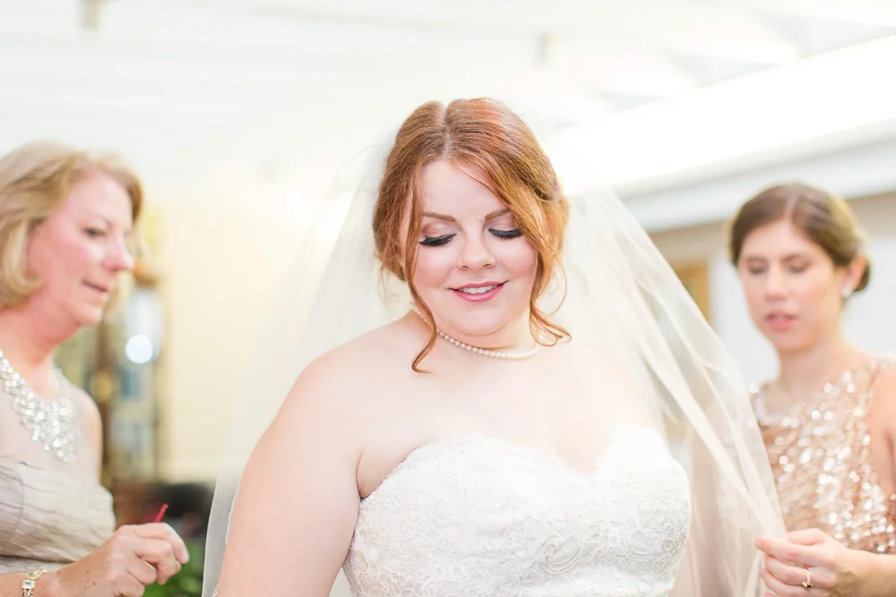 Bridesmaid adjusting the bride's veil while getting ready for the wedding