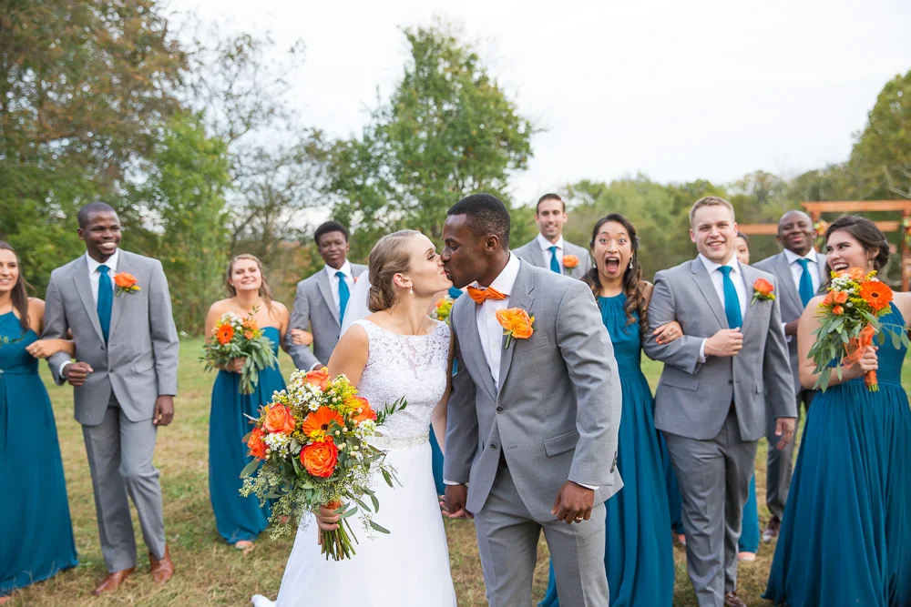 Candid wedding party photo as bride and groom kiss | Culpeper Wedding Photographer