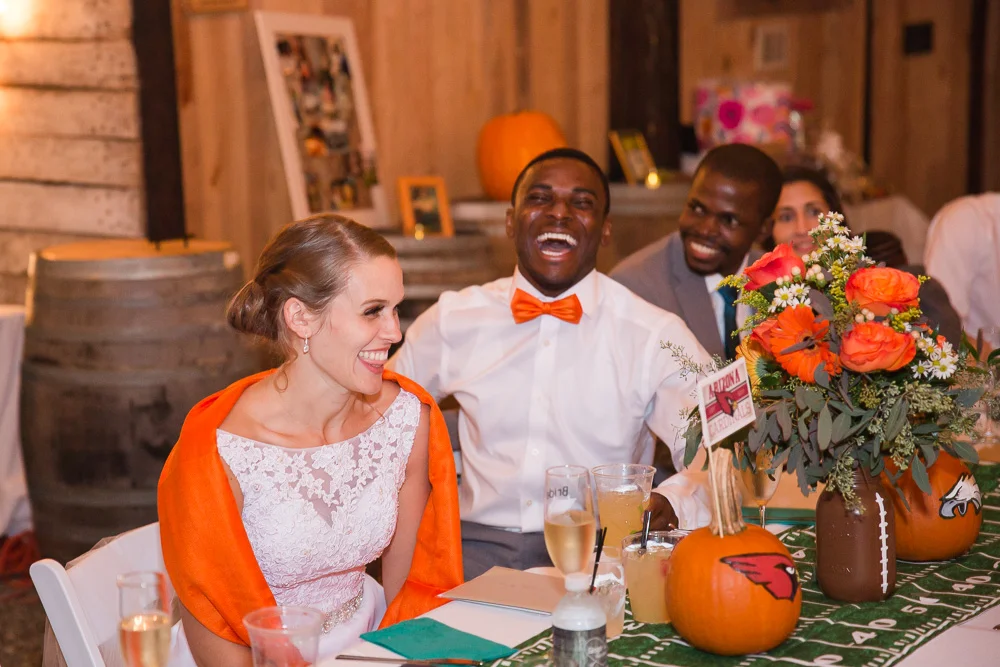 Candid laughter photo during the toasts inside the barn | Football-themed fall wedding at Mountain Run Winery