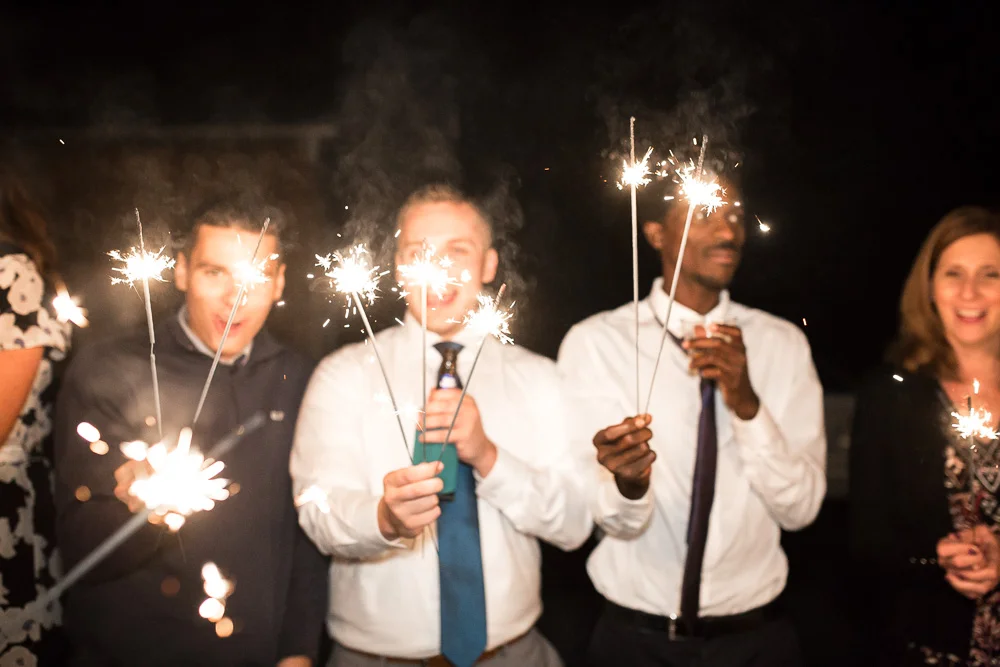 Wedding guests holding sparklers as they wait for bride and groom to exit
