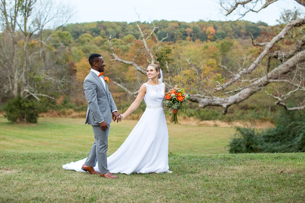 Bride and groom walking through the field near the giant oak tree at Mountain Run Winery | Candid Culpeper Wedding Photographer | Megan Rei Photography