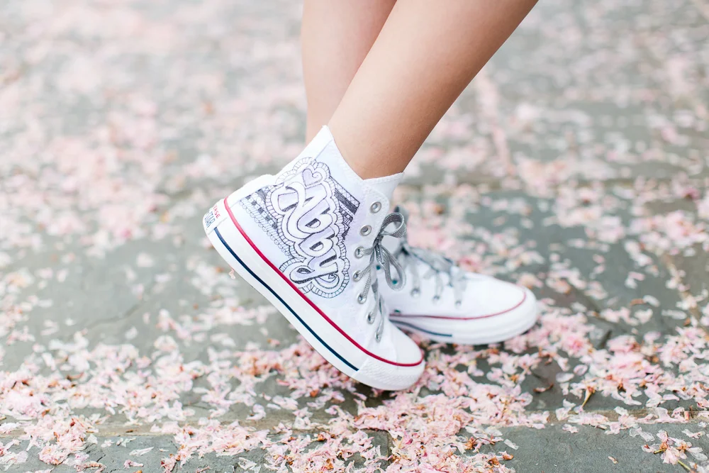 Custom sneakers made for Abby’s Bat Mitvah, surrounded by cherry blossom petals | Megan Rei Photography | Rockville, MD