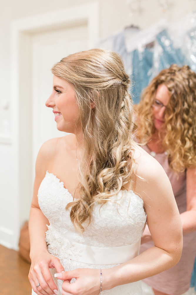 Smiling bride while putting on her wedding dress at King Family Vineyards in Crozet
