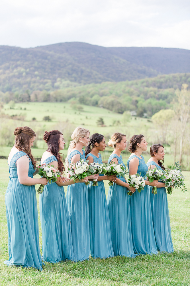 Bridesmaids in teal dresses standing during the wedding ceremony