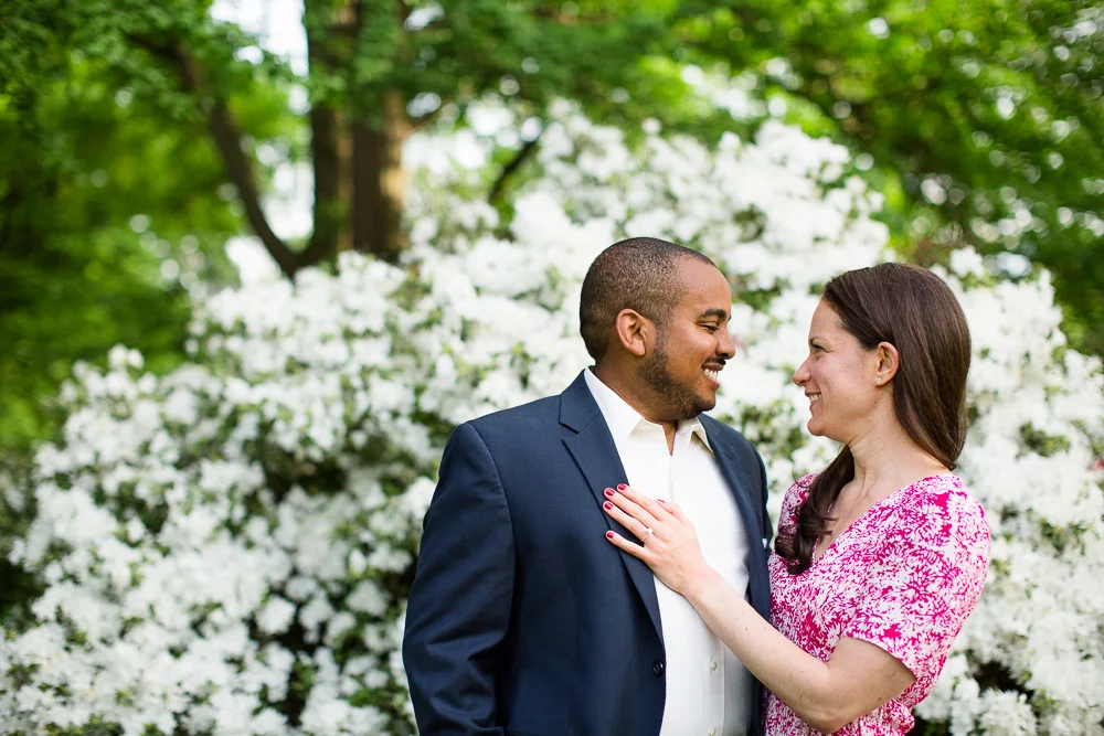 Happy engaged couple in front of white flowering bush in Central Park | Best engagement photos in NYC