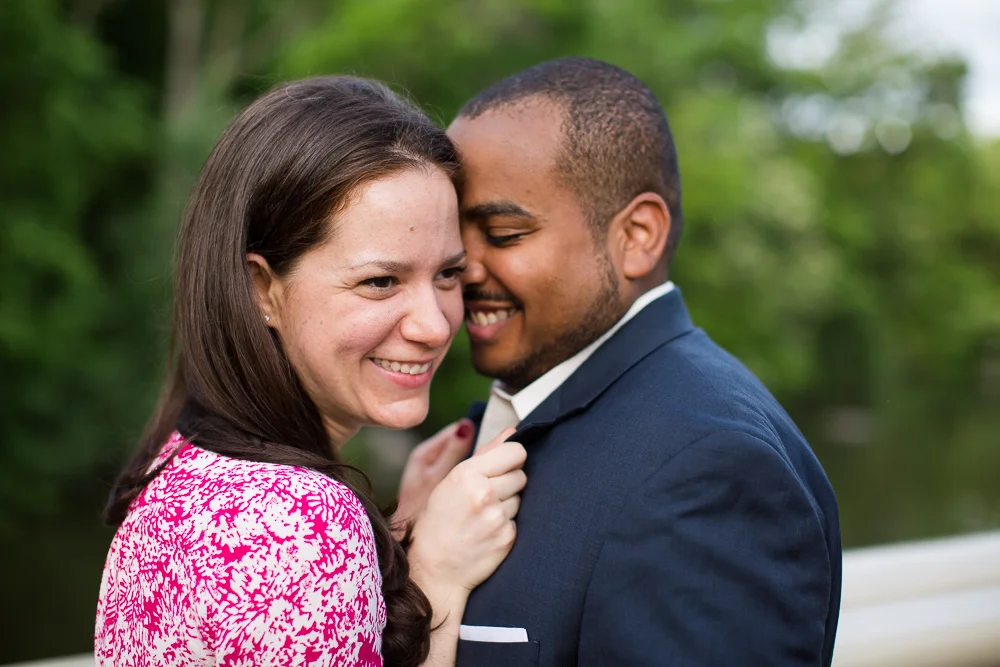 Engaged couple cuddling up on the Bow Bridge during their Central Park engagement photos