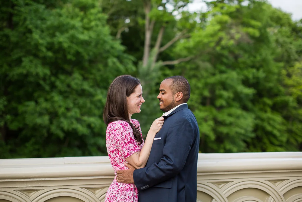 Engaged couple cuddling up on the Bow Bridge during their Central Park engagement photos