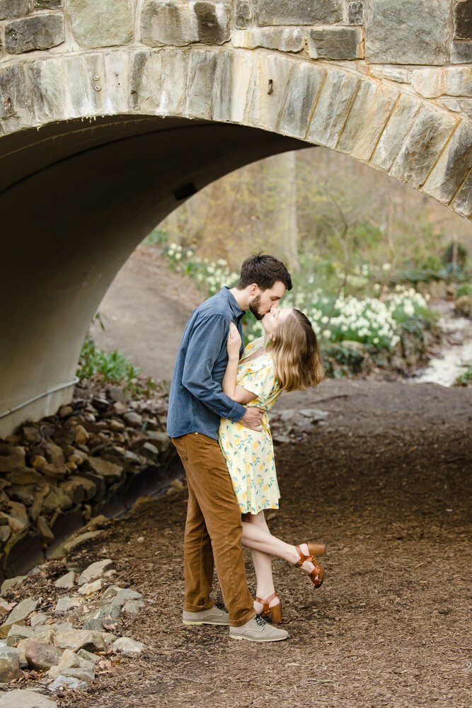 Engaged couple kisses under the bridge at Tregaron Conservancy