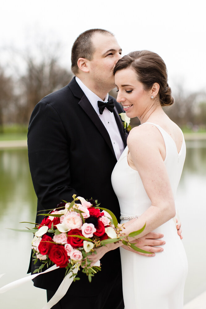 Groom kissing bride in front of the Reflecting Pool
