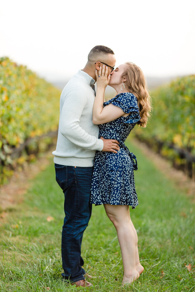 Engaged couple kissing in the vines at Stone Tower