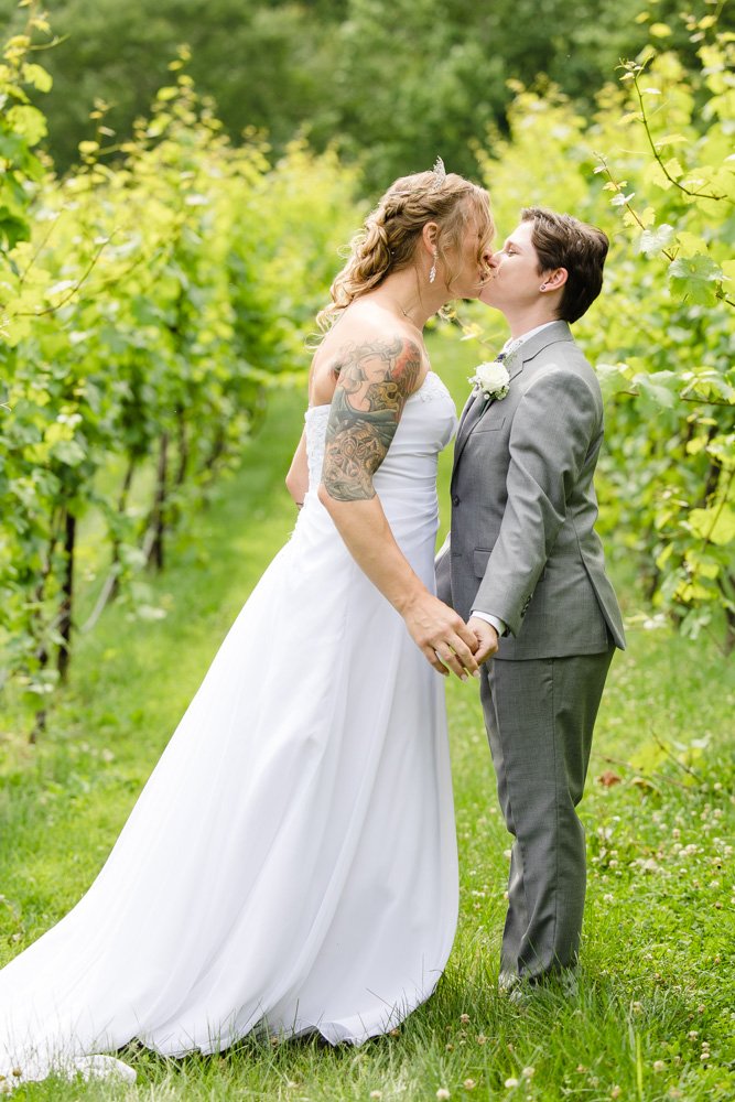 Brides kissing in the vineyard at Naked Mountain Winery
