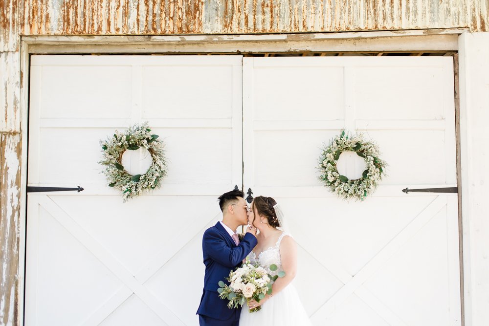 Bride and groom kiss in front of white doors at Inn at Old Silk Mill