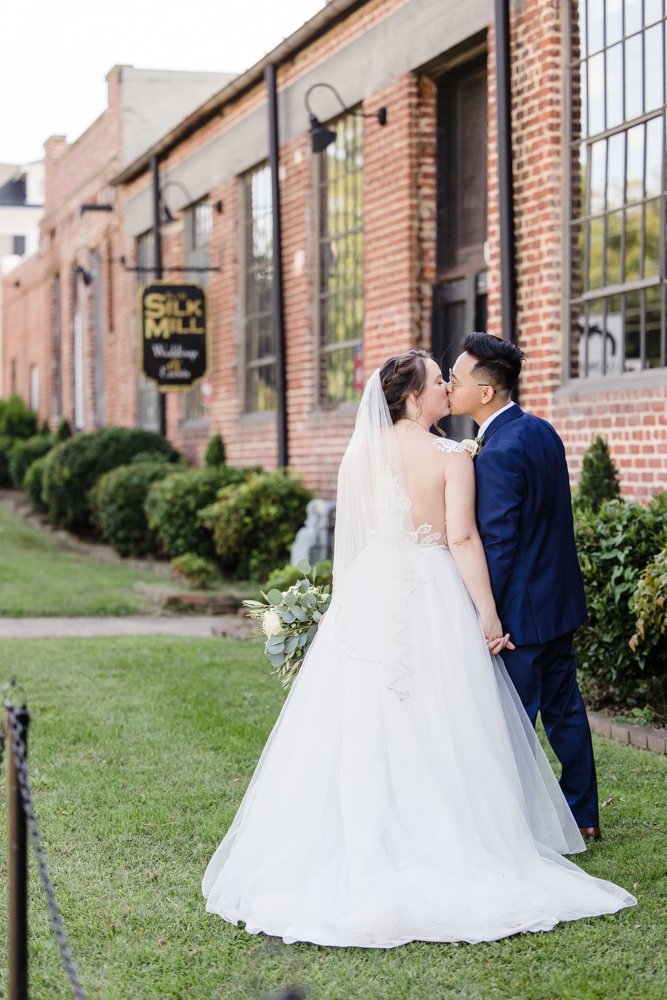 Bride and groom kissing in front of Silk Mill