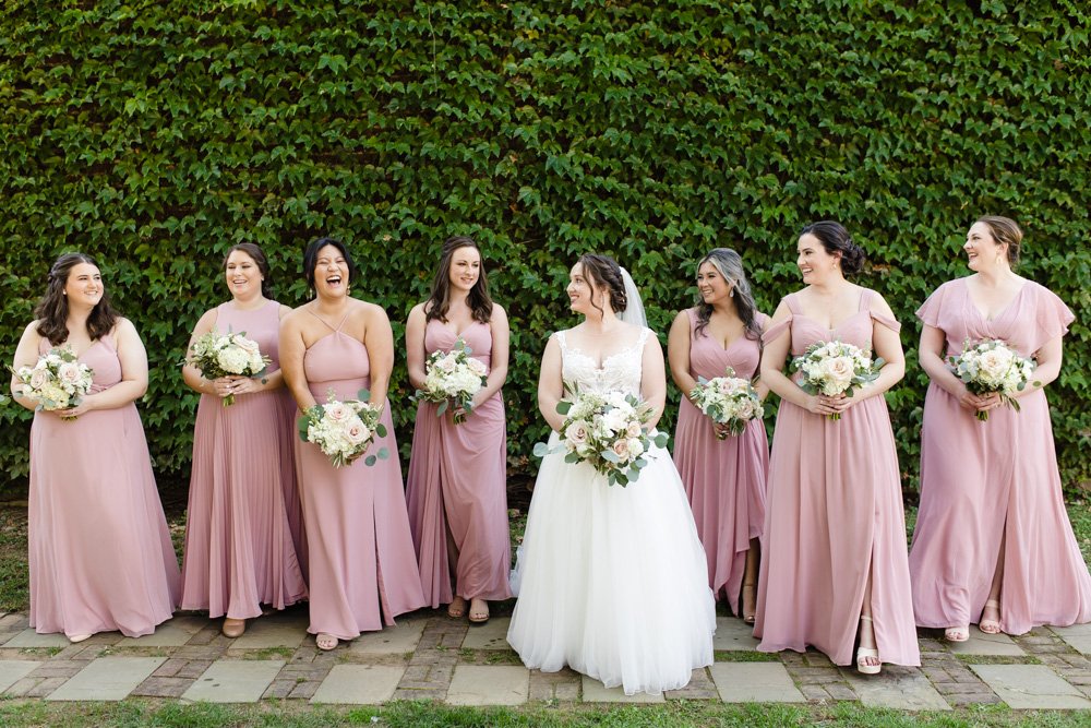 Bride with her bridesmaids in front of a wall of ivy