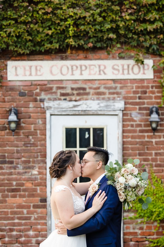 Bride and groom kiss in front of the old Copper Shop