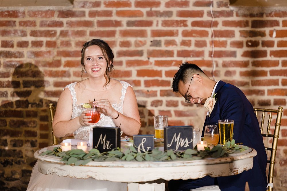 Candid photo of bride and groom laughing during toasts