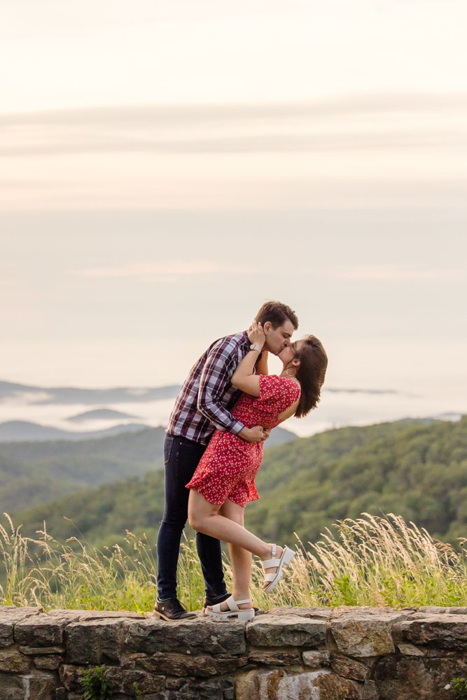 Engaged couple kisses at sunrise on Skyline Drive in Shenandoah National Park