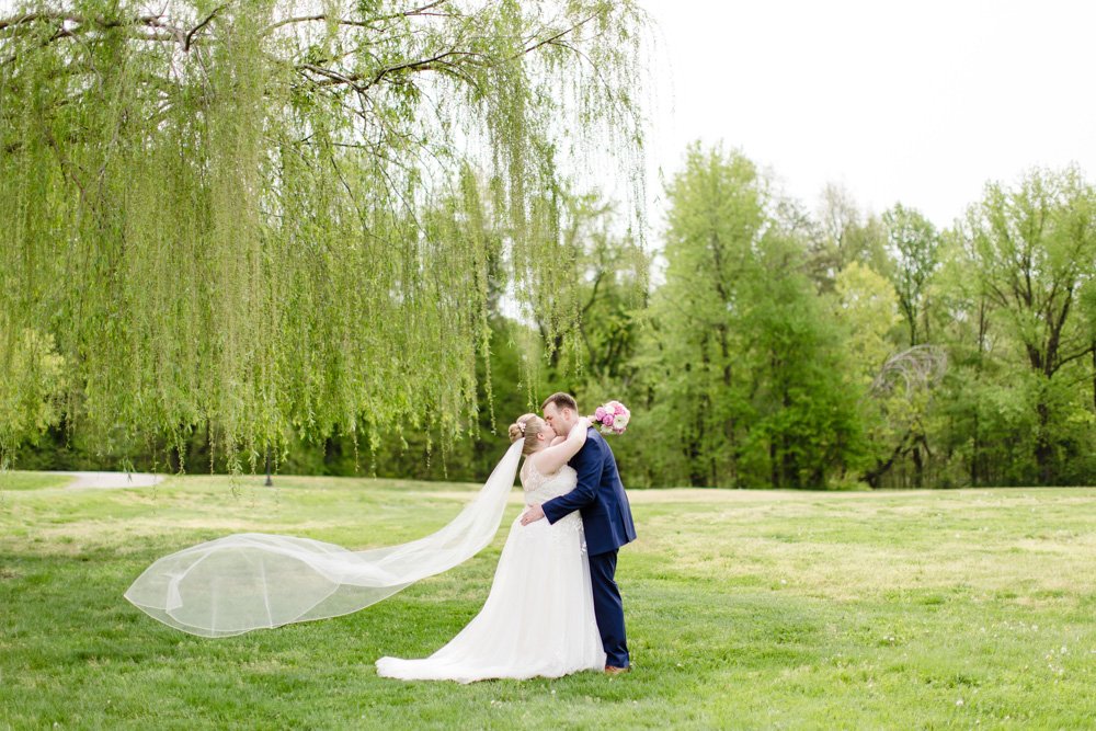 Bride and groom kiss under the willow tree at Osprey's at Belmont Bay