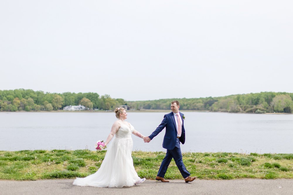 Wedding couple walking while holding hands in front of Belmont Bay