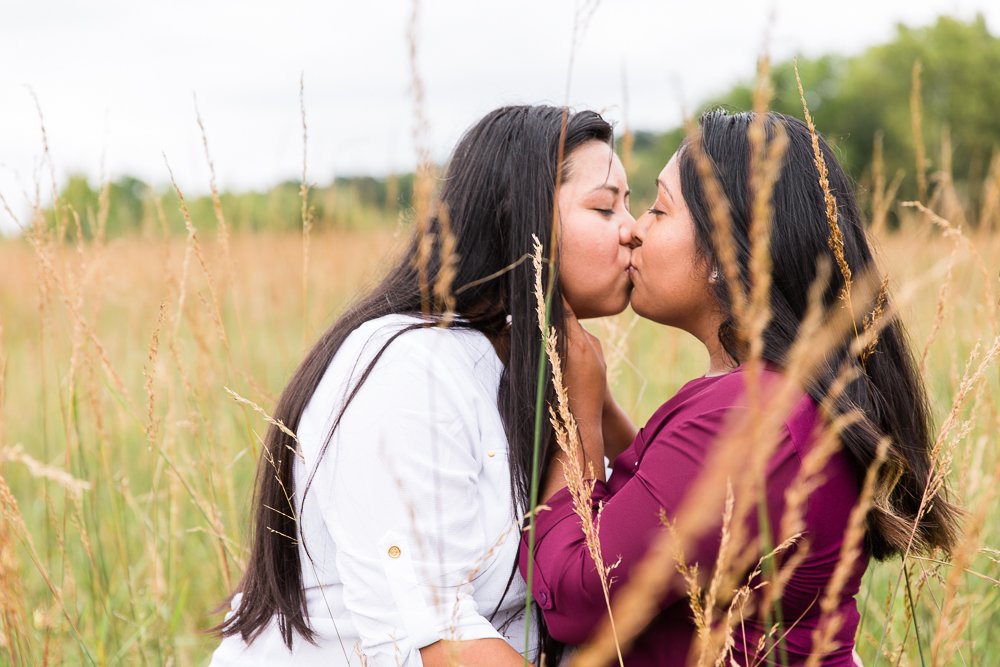 Engaged couple kisses in a field
