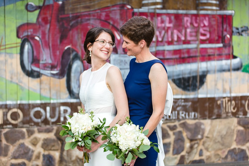 Two brides in front of the Bull Run Wines mural