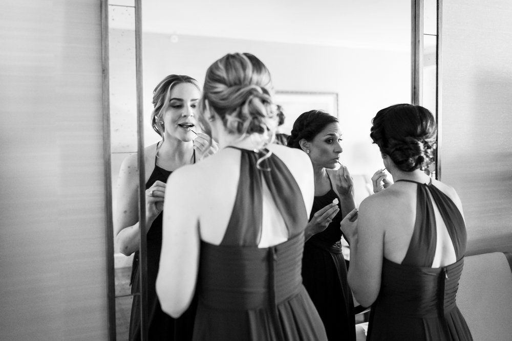 Bridesmaids putting on lipstick in the mirror