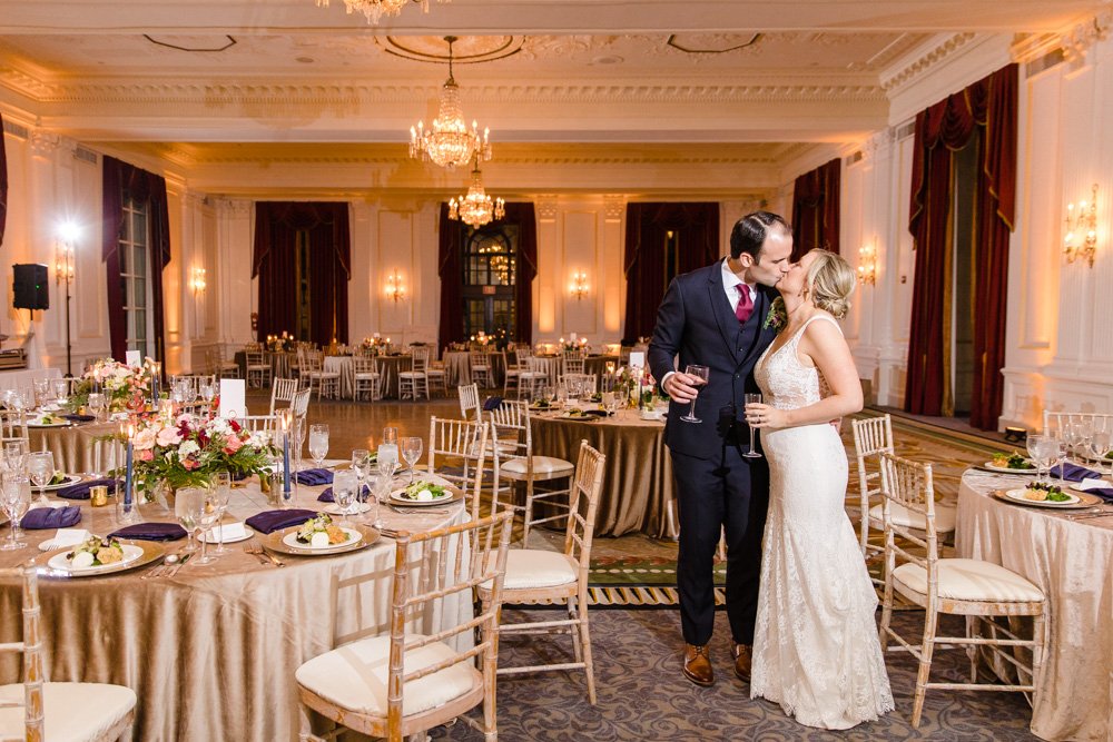 Bride and groom kiss in ballroom