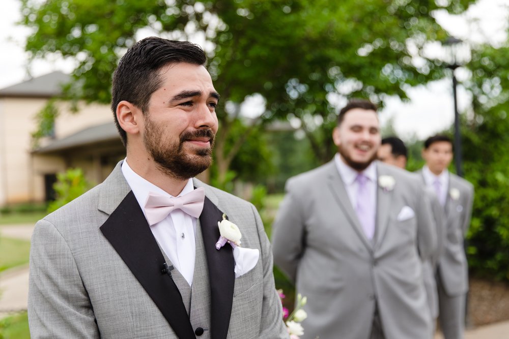 Emotional groom watching bride walk down the aisle