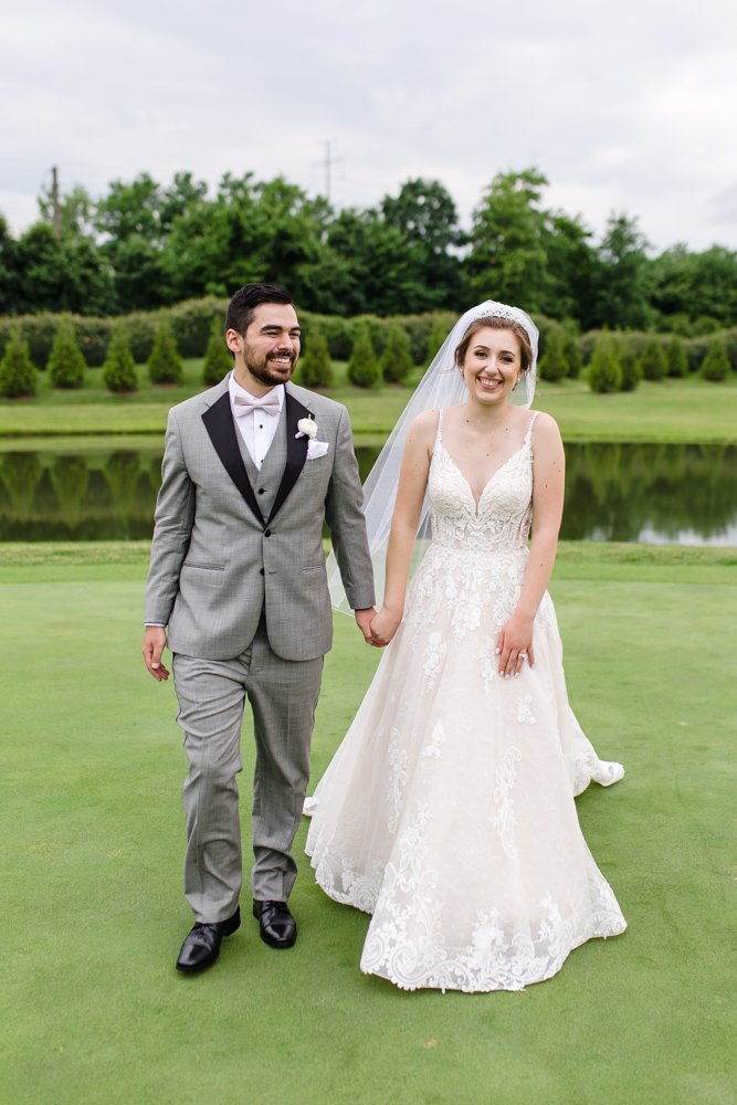 Bride and groom holding hands on the golf course
