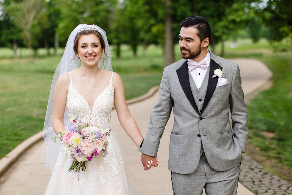 Wedding couple holding hands as they walk along the golf course