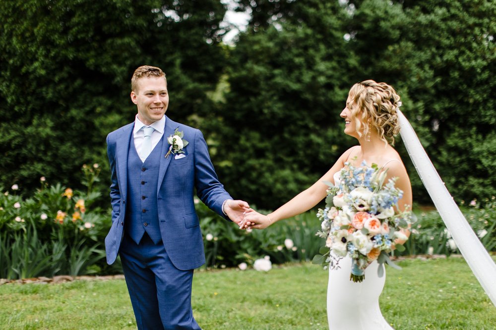  Groom holding bride’s hand and leading her across the lawn at Poplar Springs on their spring wedding day 