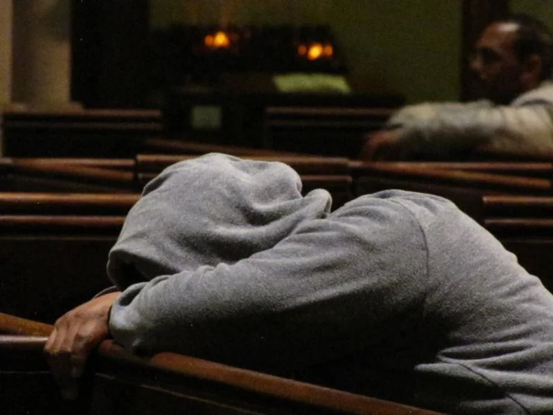 One of the many who rest in Saint Mary's whenever our doors are open. In the background a parishioner prays.