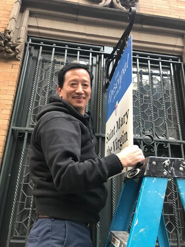 Sexton Harka Gurung hanging a new sign on 47th Street. 