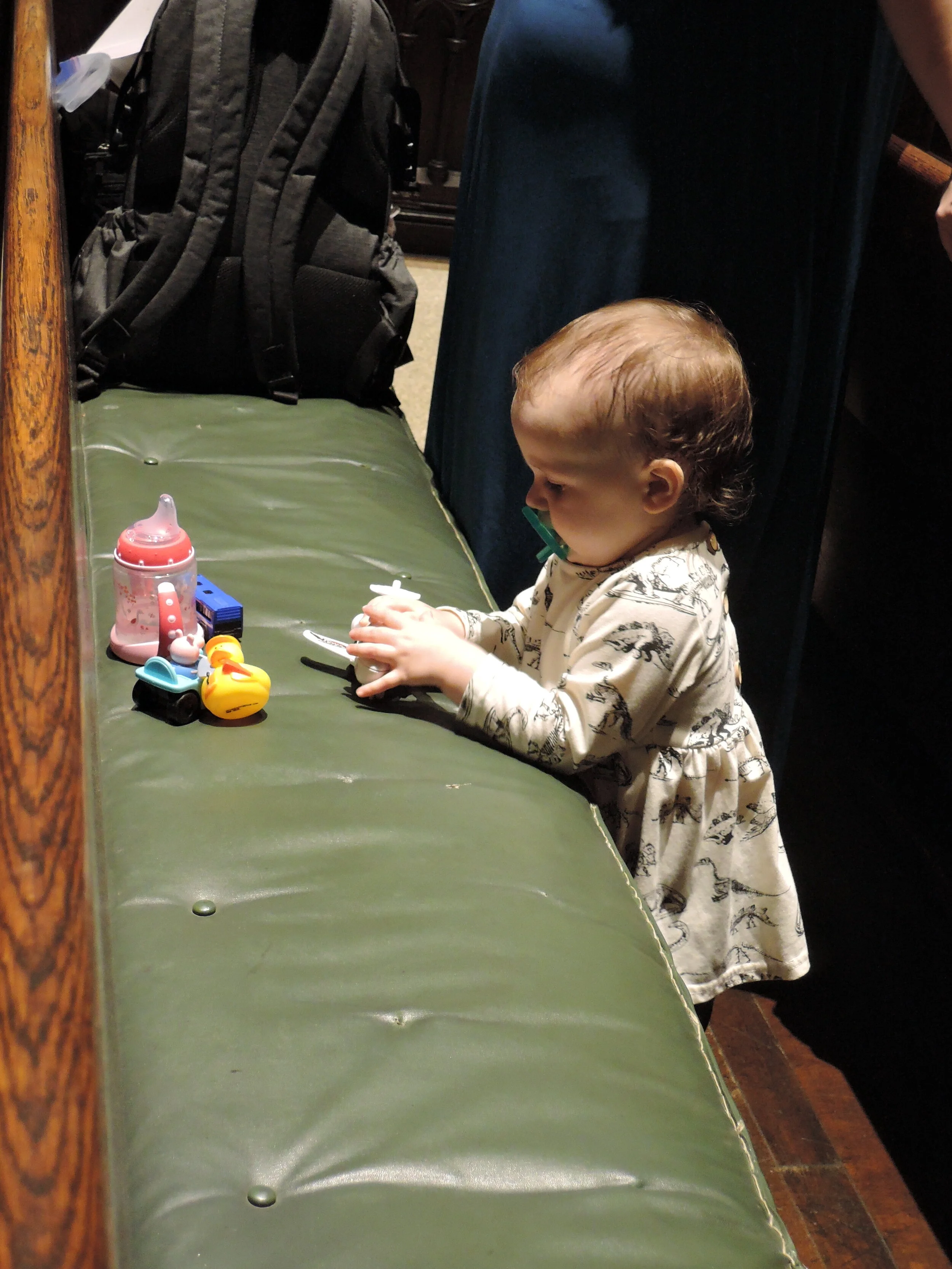 A young communicant during the sermon. Carried in her mother's arm, she came to the altar rail with her hand stretched out to receive the Bread. Photo: Grace Mudd