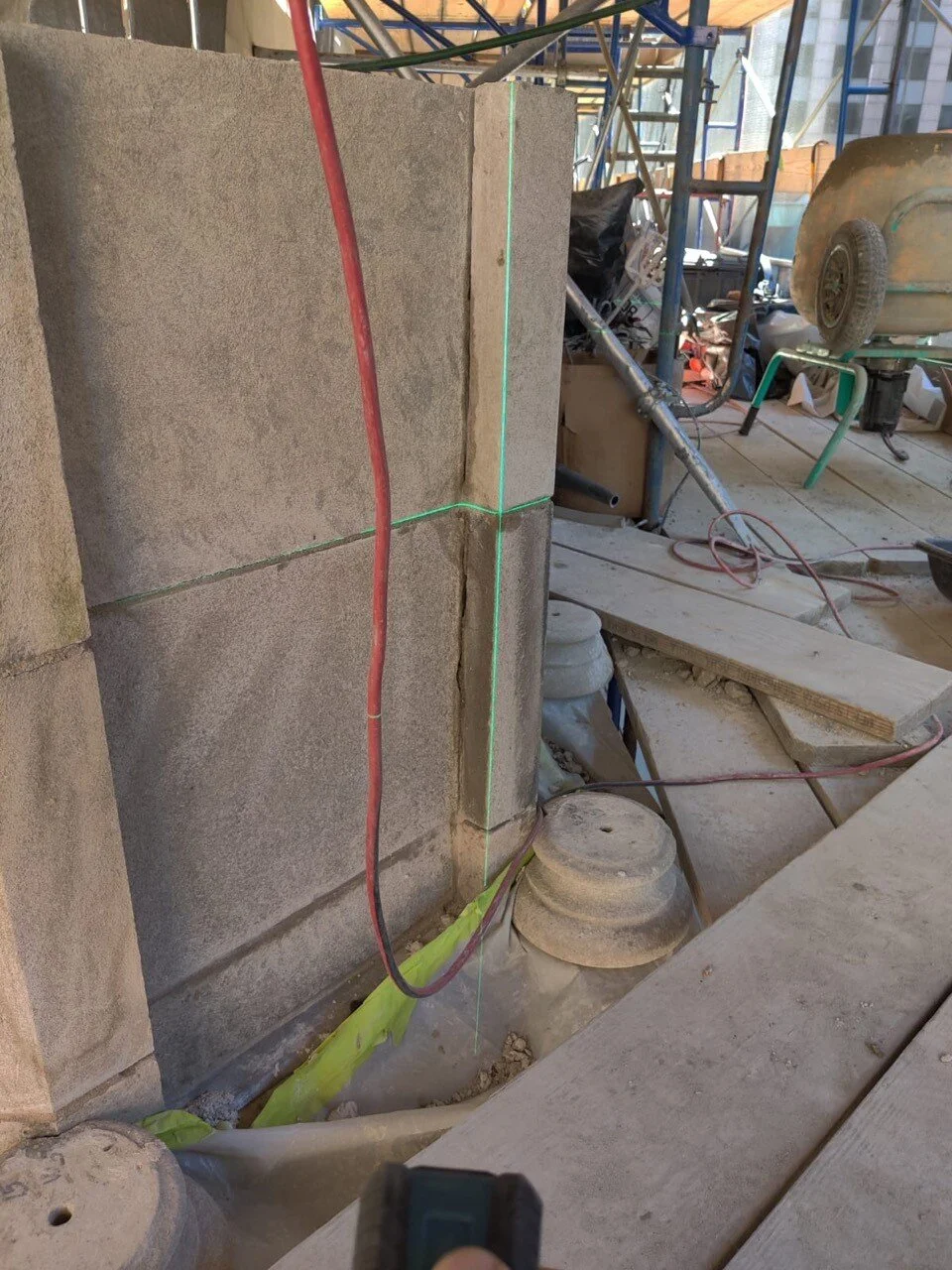 The stones that will form the base on which the cross at the pinnacle of the church roof is set are being placed. The green line is a laser light used to assist the placement. Photo: Milan Restoration