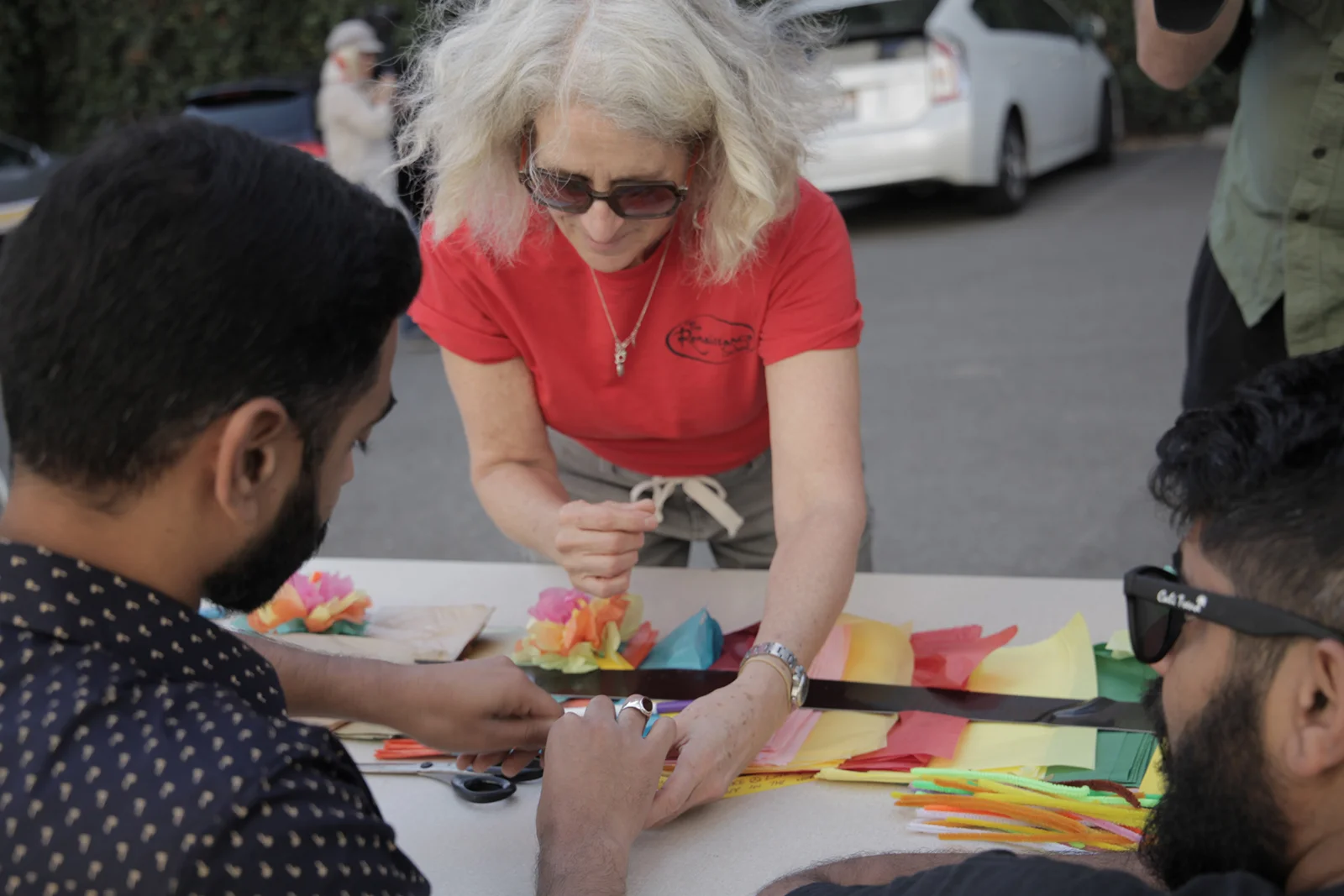 Robin Bernstein (center) teaches Shayan Mehdi (left) how to make a flower out of tissue paper. - Bay area residents create art protesting the Travel Ban. October, 2017.