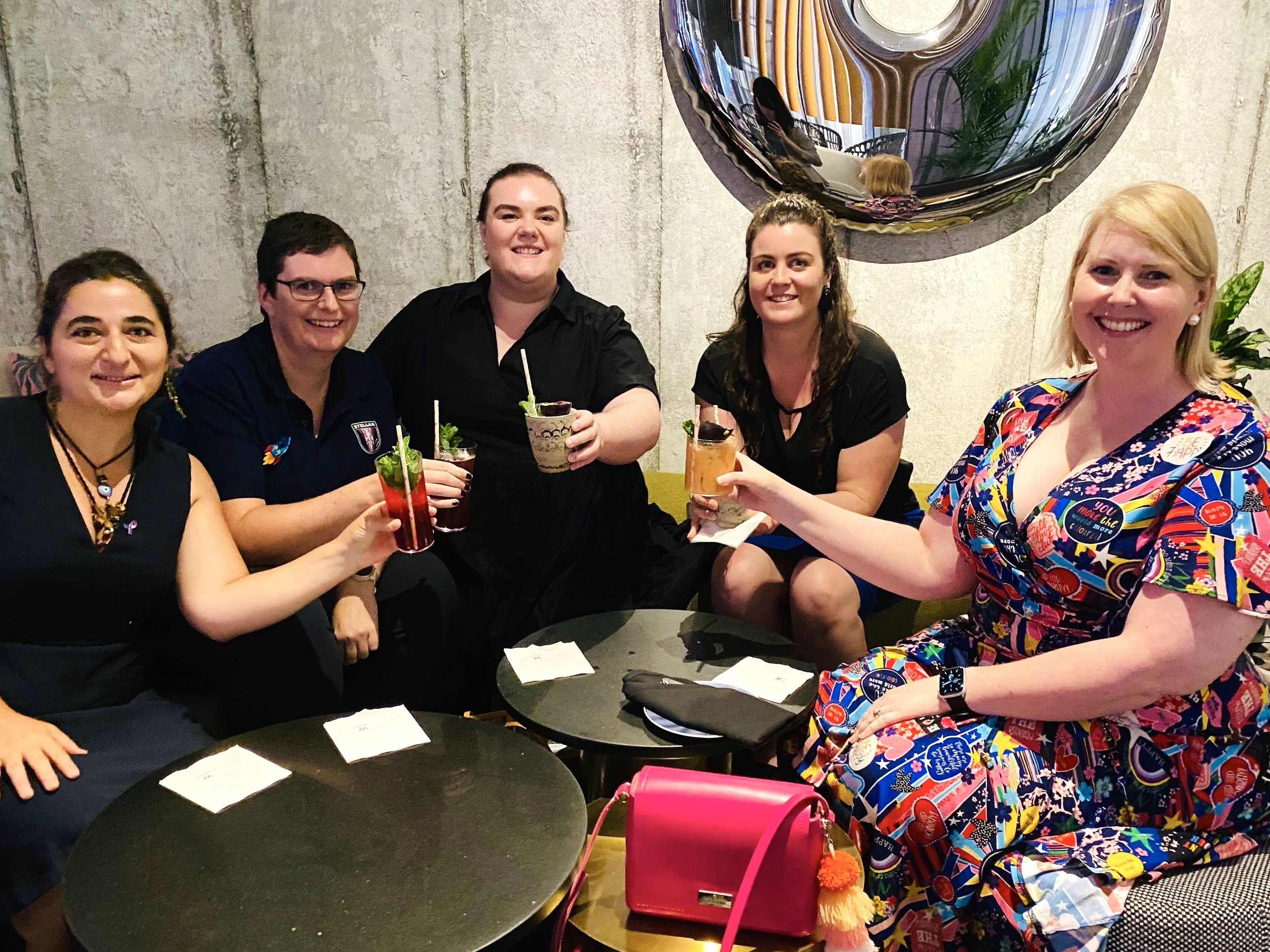  DPA committee members around a table cheering with drinks. 