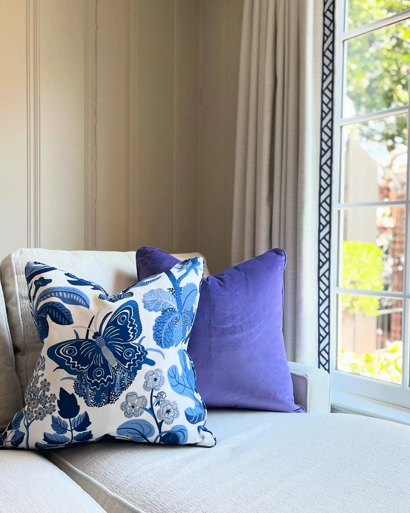 Sunlight, soft textures, and a touch of Schumacher magic 💫 The butterfly print pillow brings whimsy and charm, while the tailored trim on the drapery frames the window like a work of art. The violet pillows are a perfect match to the blooms in my cl