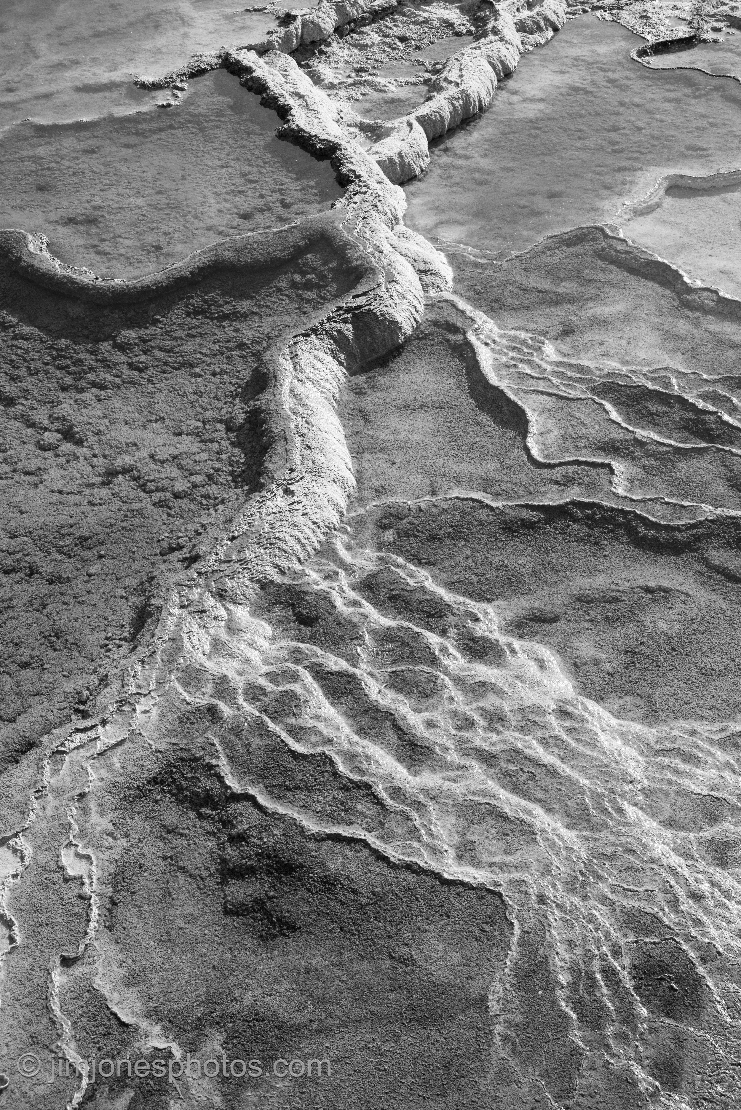 The travertine terraces and pools at Mammoth Springs in Yellowstone form distinct patterns and shapes. These formations come from minerals in the water and have been formed over thousands of years. A wood-covered walking path makes it easy to access