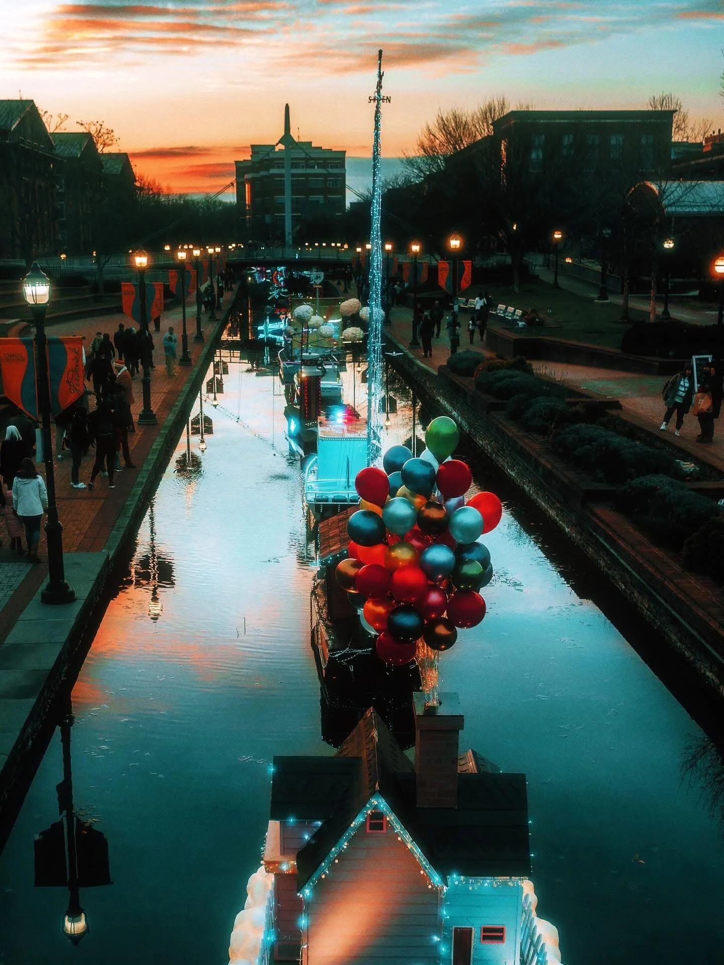 Decorated boat with colorful balloons and house with Christmas lights on a waterway at sunset in Frederick, Maryland.