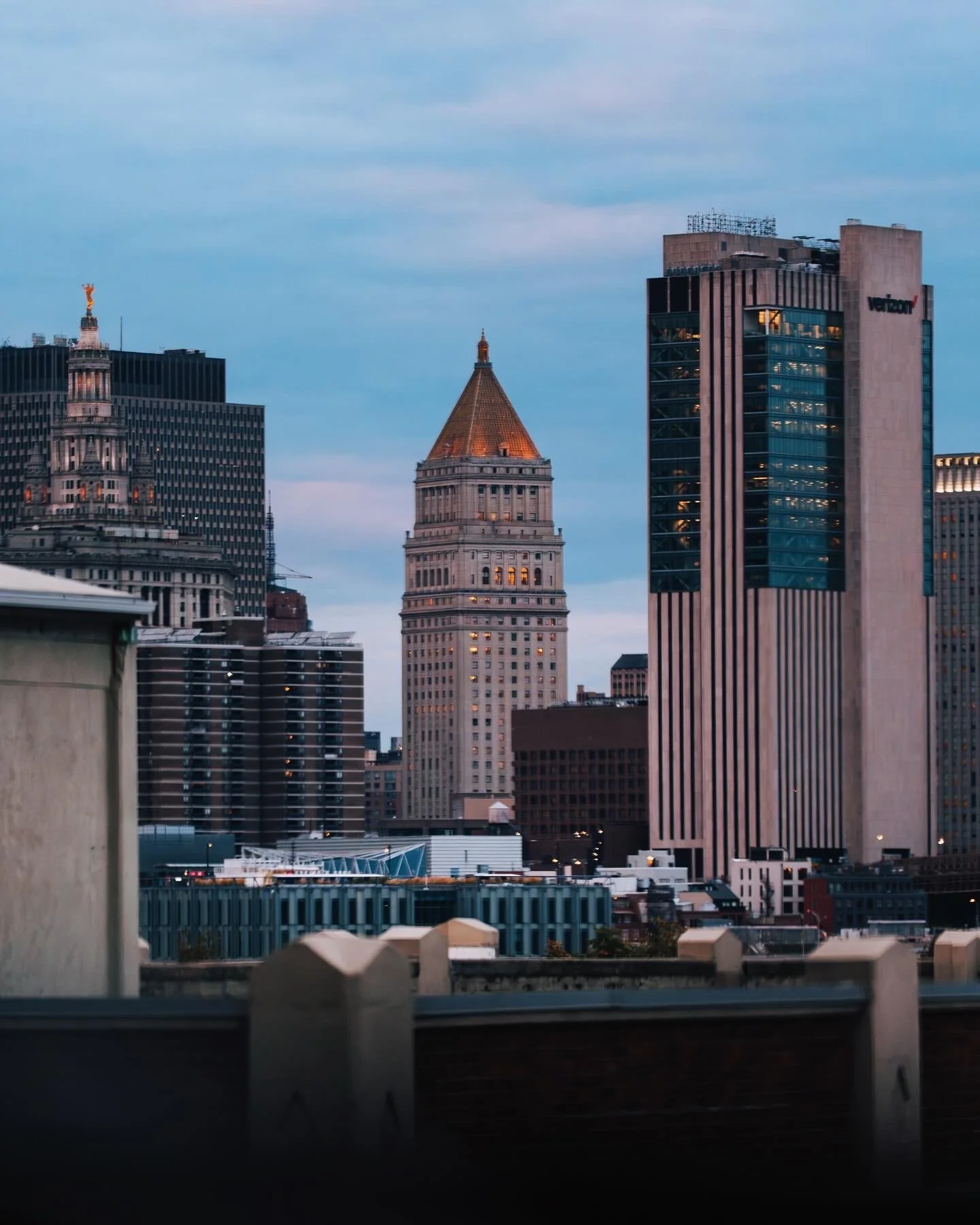 City skyline at dusk featuring the Millennium Tower and other skyscrapers with blue sky and clouds.