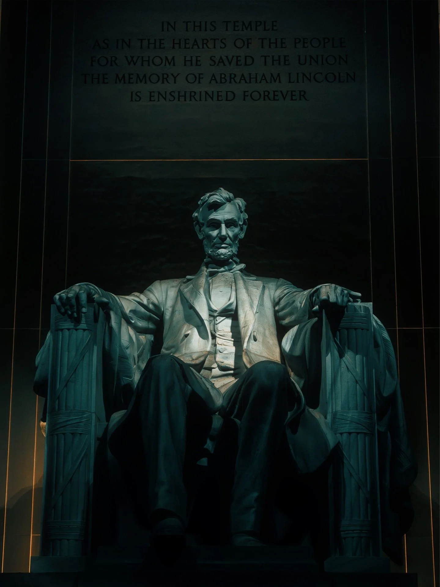 The Lincoln Memorial statue of Abraham Lincoln seated in a chair with an inscription above it that reads, "In this temple as in the hearts of the people for whom he saved the union the memory of Abraham Lincoln is enshrined forever."