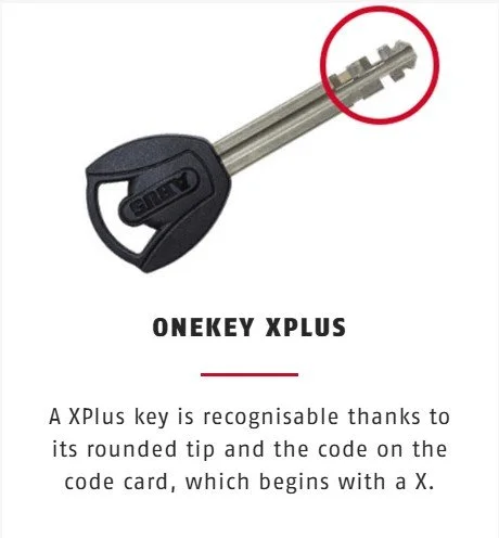 A metal key with a black plastic handle, labeled "ONEKEY XPLUS," featuring a rounded tip and a code on the key blade.
